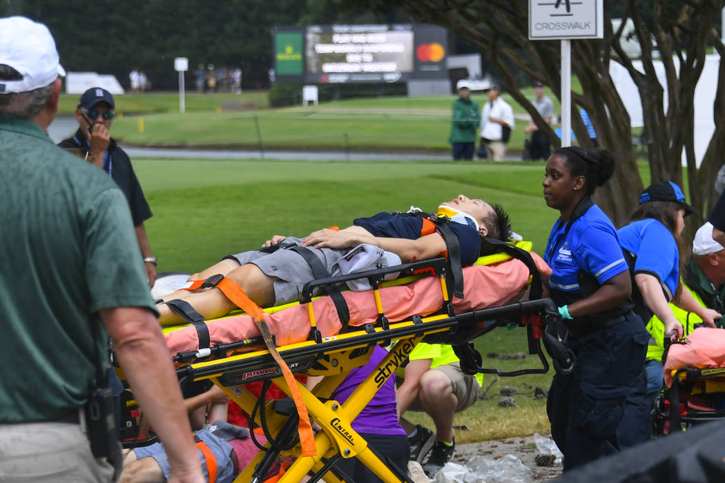 A spectator is taken to an ambulance after a lightning strike on the course which left several ...