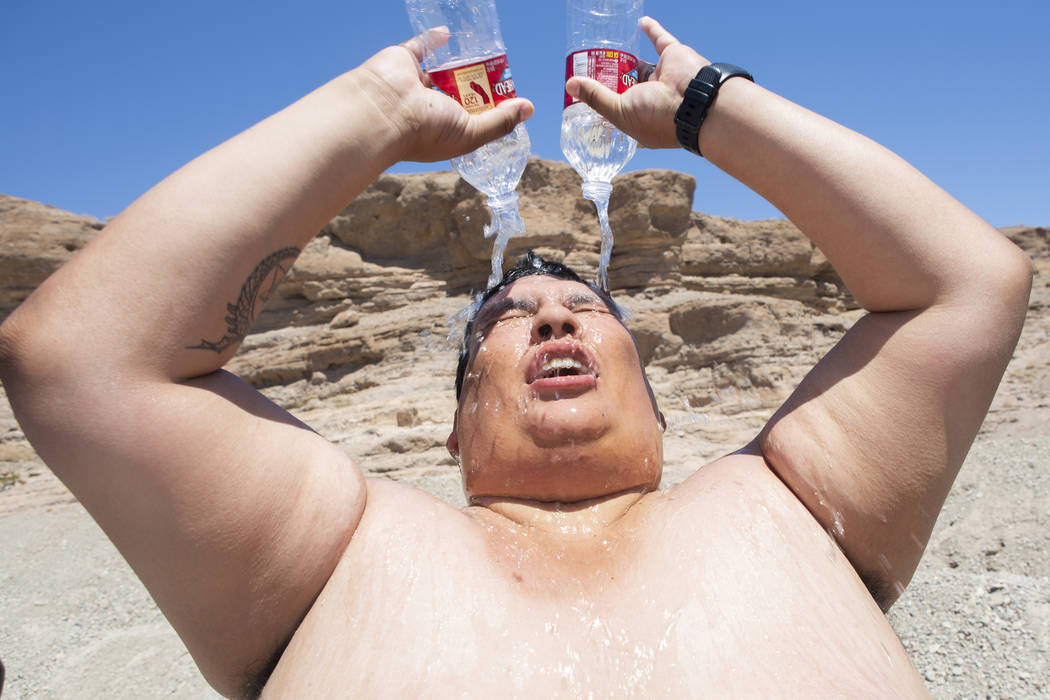 Omar Ramirez, 29, bathes with two water bottles during a hot summer day in the sun after pickin ...