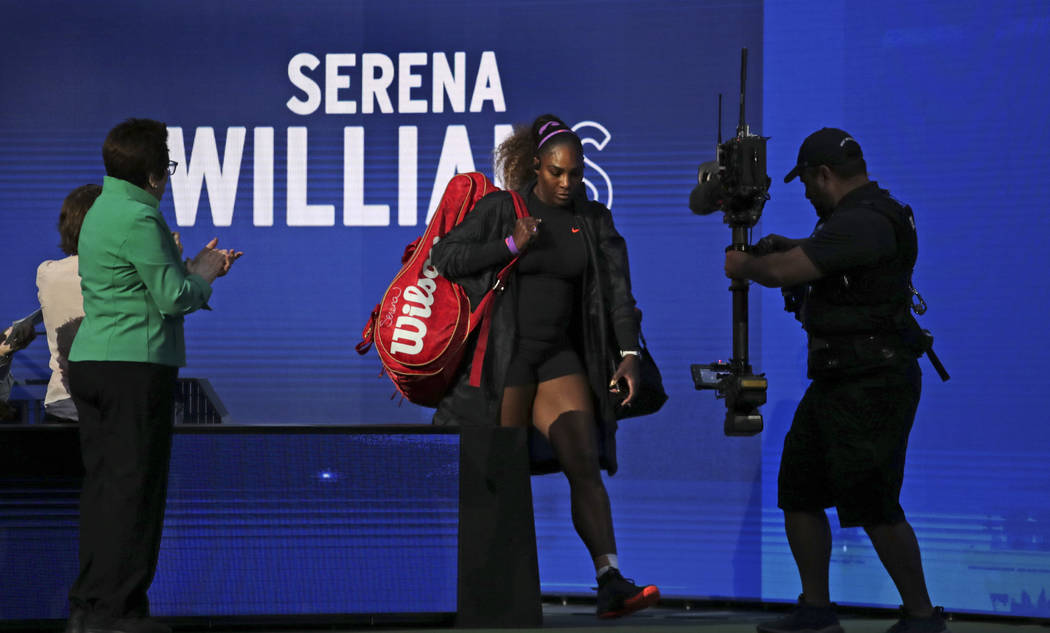 Serena Williams, center, walks onto the court to face Maria Sharapova in their first-round matc ...