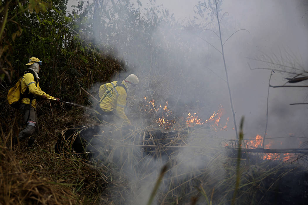 Firefighters work to put out fires along the road to Jacunda National Forest, near the city of ...