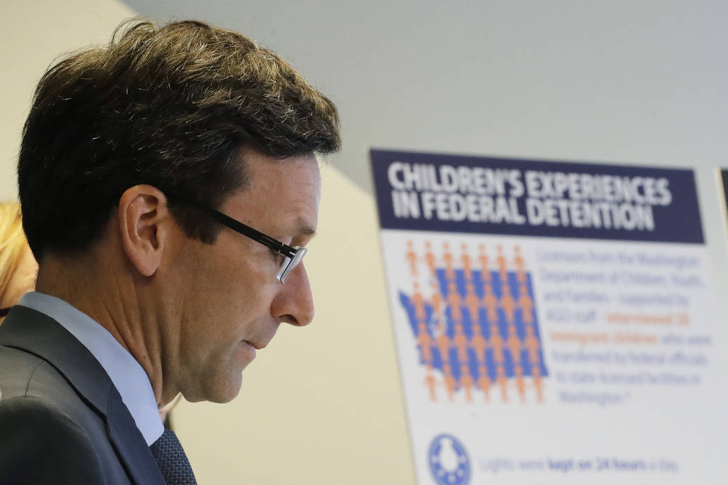 Washington Attorney General Bob Ferguson listens to a question as he stands next to a display b ...