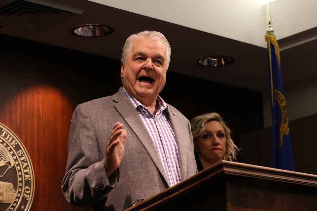 Gov. Steve Sisolak, center, speaks during a news conference at the Grant Sawyer State Office Bu ...