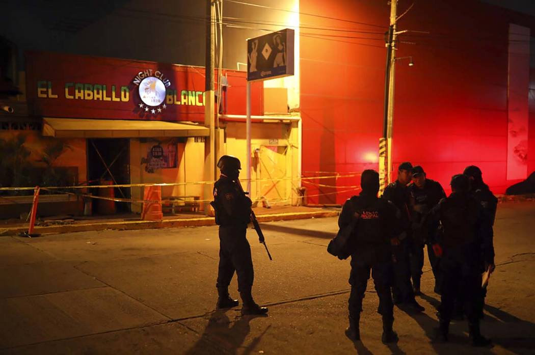 Police officers guard the scene outside a bar where more than 20 people died in an overnight at ...