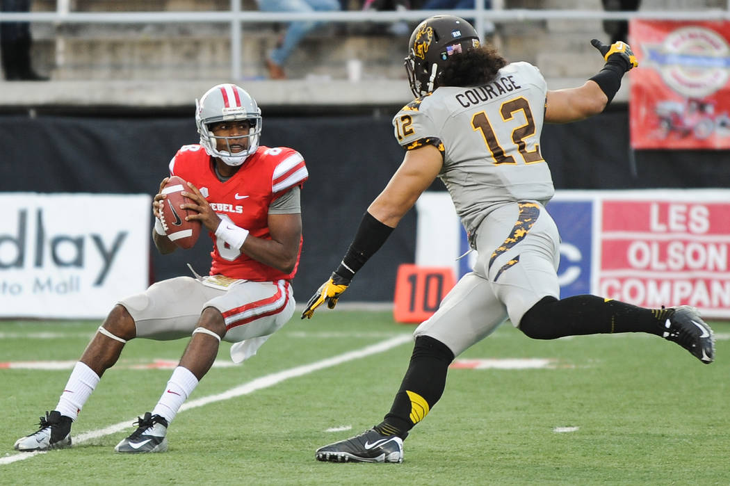 UNLV quarterback Caleb Herring (8) is pressured by Wyoming's Sonny Puletasi (12) during a footb ...