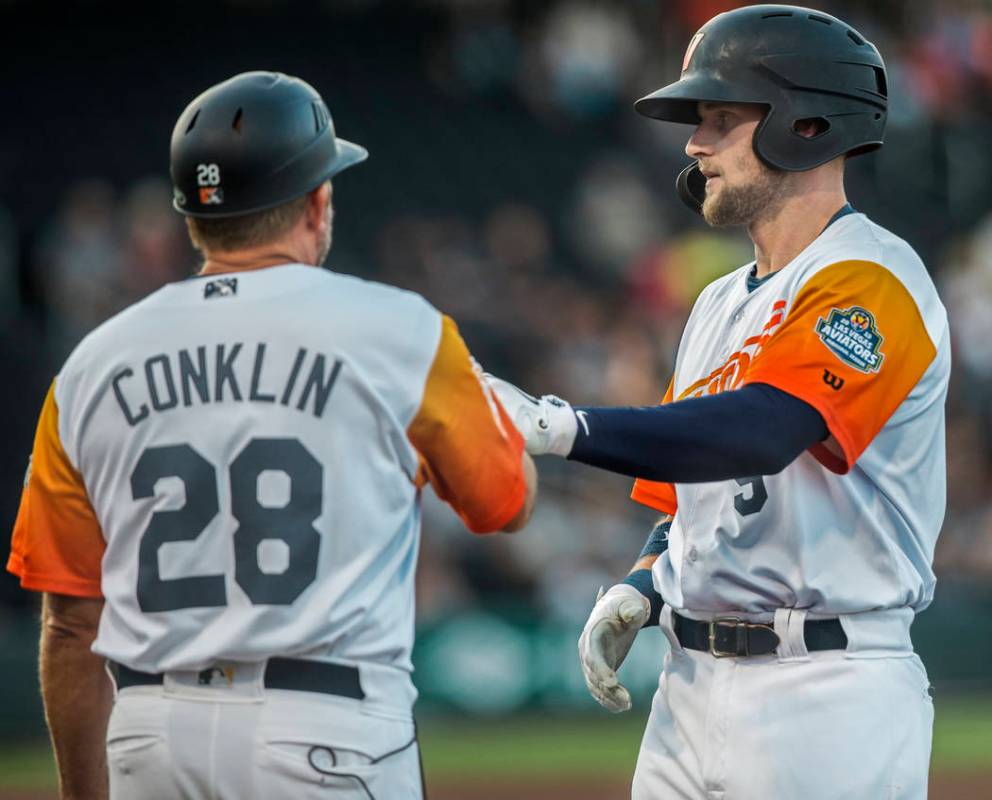 Las Vegas Aviators first baseman Seth Brown (9) high fives first base coach Craig Conklin (28) ...