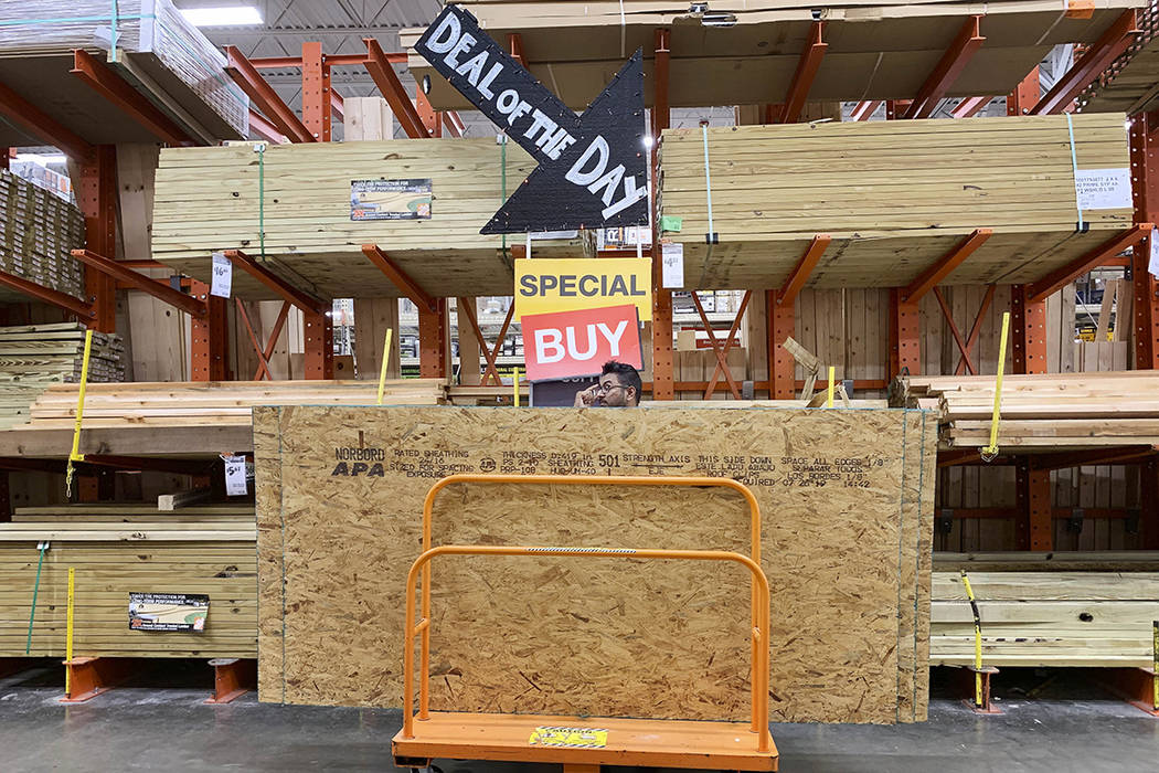 A shopper stands with a dolly of plywood at The Home Depot ahead of Hurricane Dorian on Thursda ...