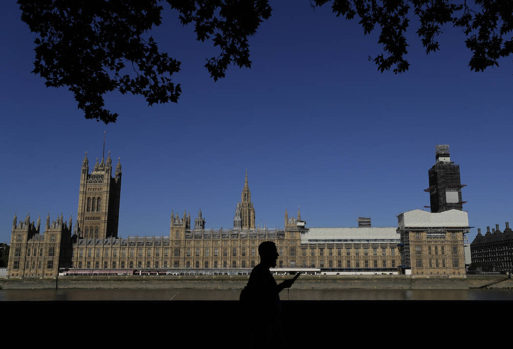 A pedestrian passes Britain's Houses of Parliament on the bank of The River Thames in London, T ...