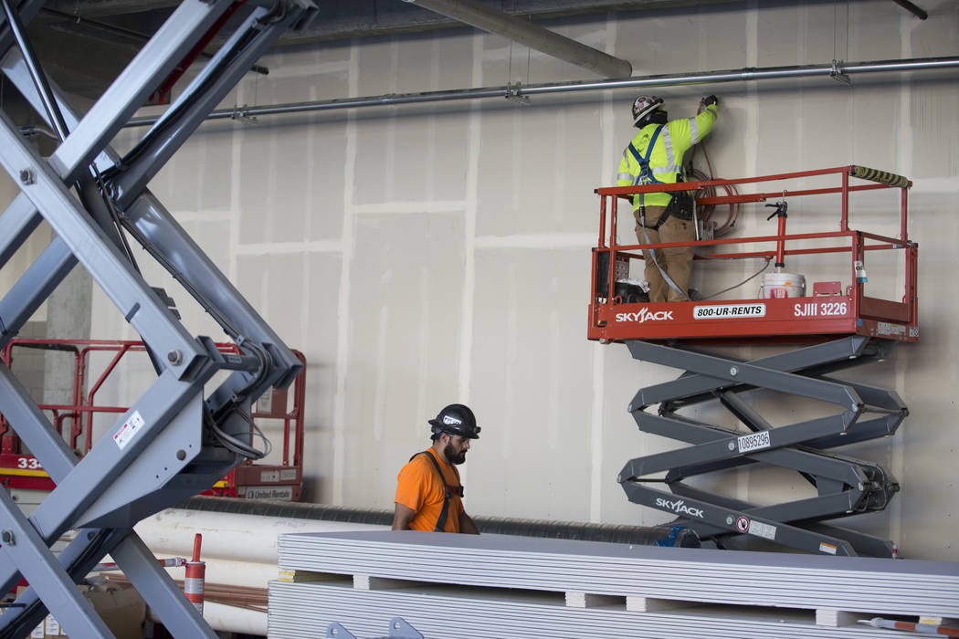 A worker, right, patches a wall at the Raiders Allegiant Stadium construction site in Las Vegas ...