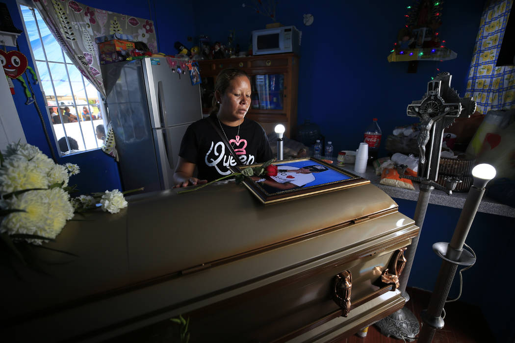 Vanessa Galindo Blas, 32, places a rose on a photograph atop the coffin of her late husband Eri ...