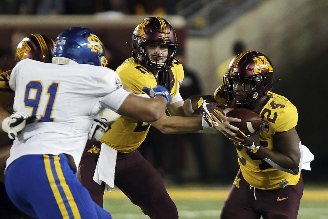 Minnesota quarterback Tanner Morgan (2) hands the ball off to running back Mohamed Ibrahim (24) ...