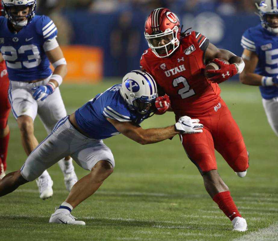 Utah running back Zack Moss, right, is tackled by BYU defensive back Austin Lee during the firs ...