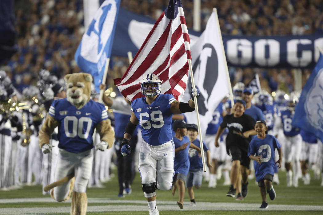 BYU offensive lineman Tristen Hoge (69) carries a U.S. flag onto the field before the team's NC ...