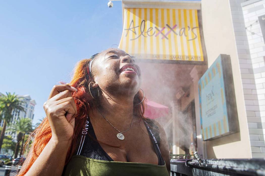 Shelle Ralph from North Carolina cools off from the heat with the water mist outside of Alexxa' ...