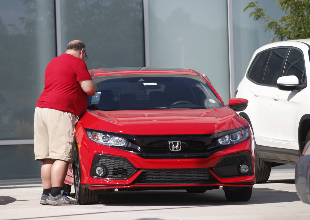 In this Aug. 25, 2019, photograph, a prospective buyer checks over an unsold 2019 Civic sedan o ...