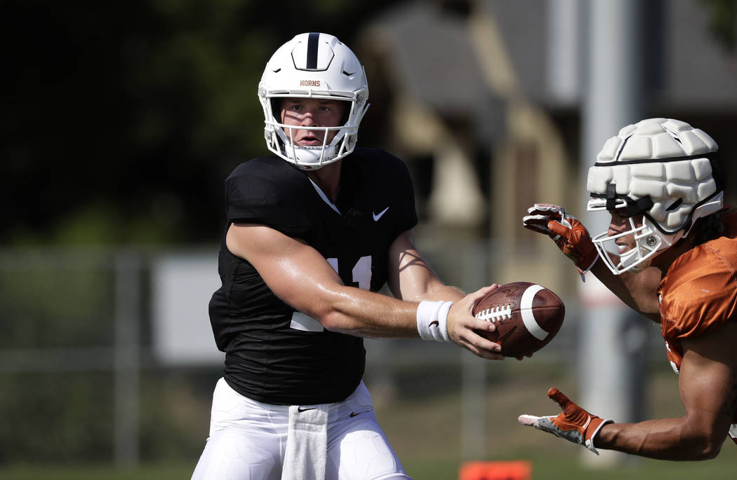 Texas quarterback Sam Ehlinger, left, and running back Jordan Whittington, right, take part in ...