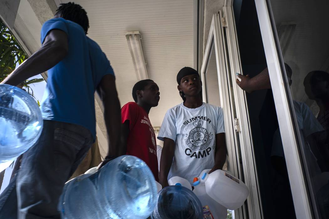 People line up to buy water at a store before the arrival of Hurricane Dorian, in Freeport, Bah ...