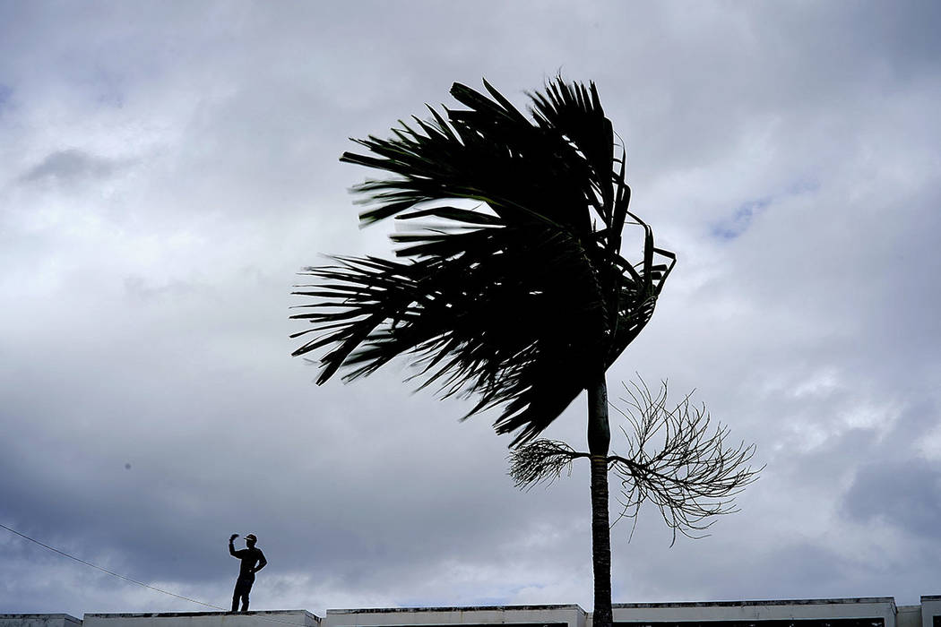 A man stands on a store's roof as he works to prepare it for the arrival of Hurricane Dorian in ...