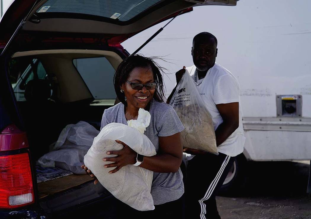 Yolande Rolle carries sandbags to place at her shop's doorstep as she prepares for the arrival ...