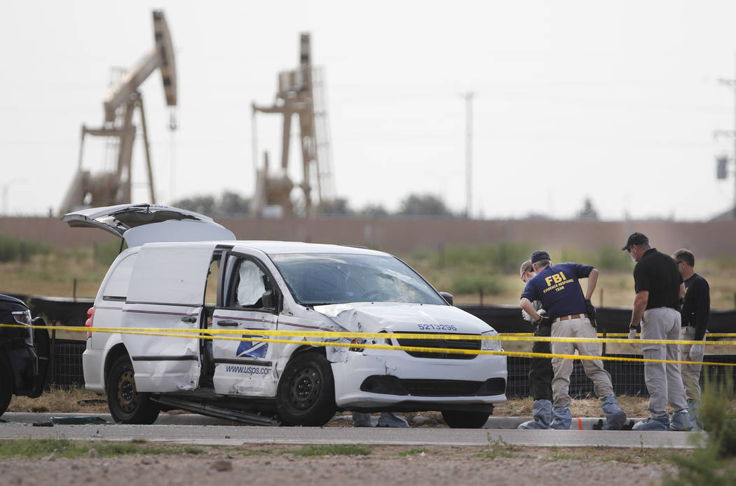 Authorities look at a U.S. Mail vehicle, which was involved in Saturday's shooting, outside the ...