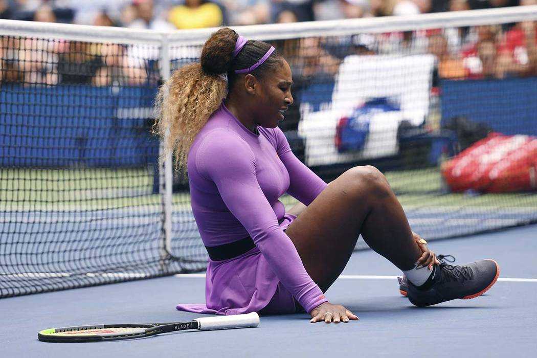 Serena Williams, of the United States, grabs her ankle after falling while chasing a return aga ...
