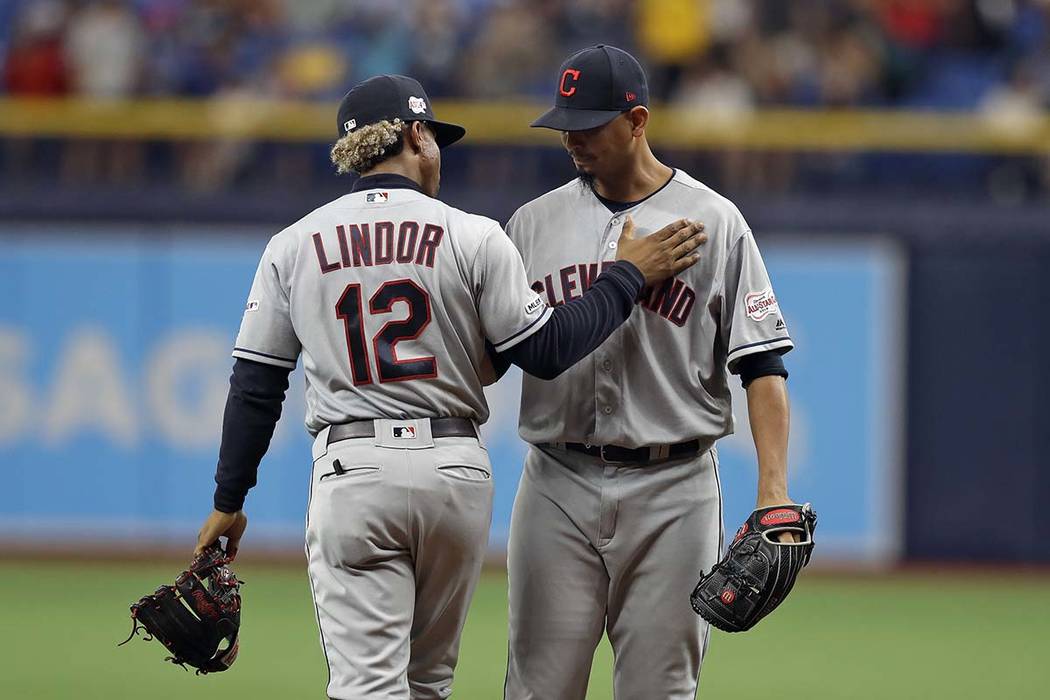 Cleveland Indians shortstop Francisco Lindor (12) pats Indians pitcher Carlos Carrasco on the c ...