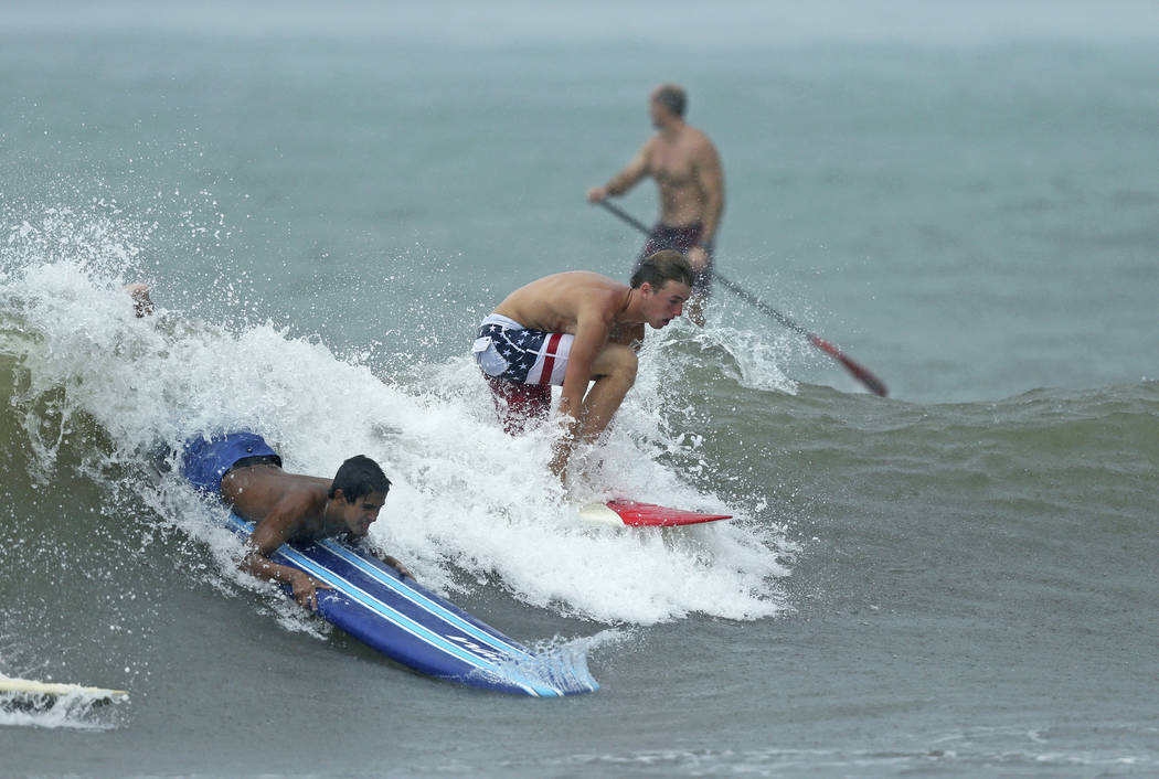 Surfers take advantage of waves at Anglin's Fishing Pier in Lauderdale-By-The-Sea, Fla., Monday ...