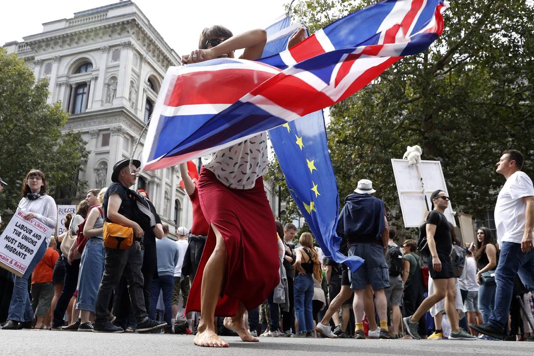 An anti Brexit protester waves the flags of European Union and Britain during a rally outside D ...