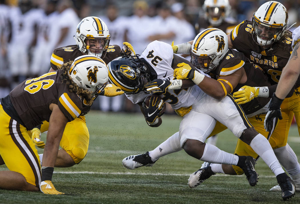 Wyoming defenders Cassh Maulia (46), Logan Wilson (30)and Mario Mora (97) tackle Missouri runni ...