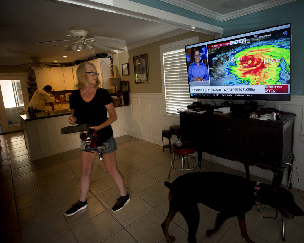 Kristie Fisher, center, catches the latest on Hurricane Dorian on television at the home of her ...