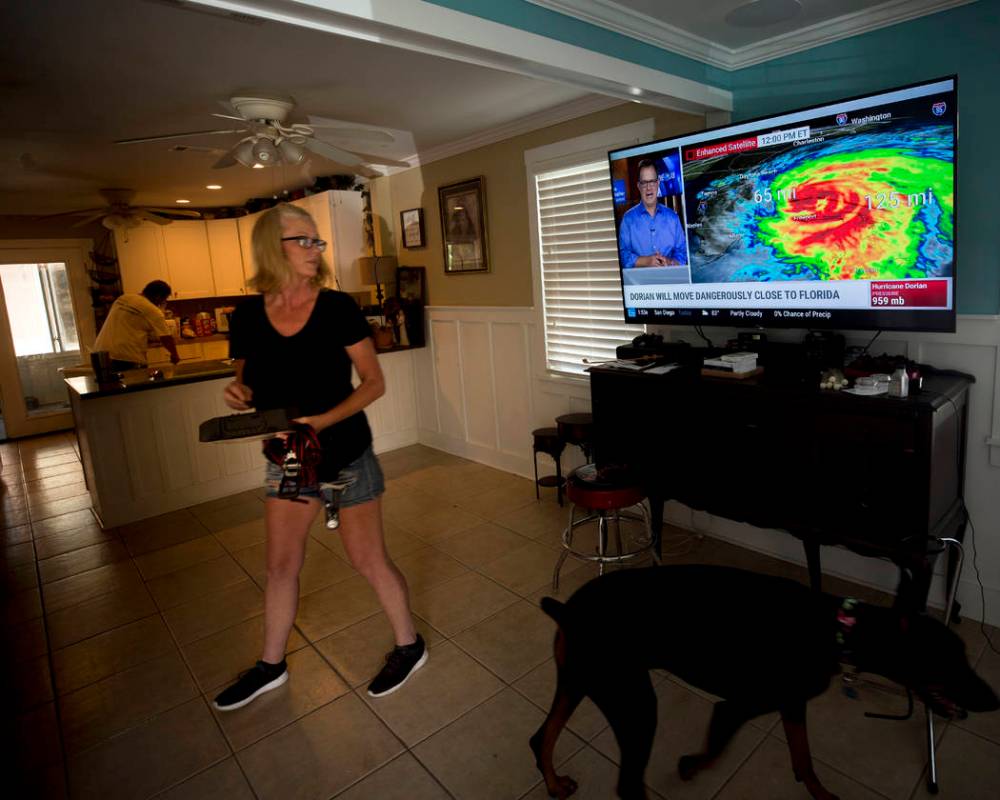 Kristie Fisher, center, catches the latest on Hurricane Dorian on television at the home of her ...