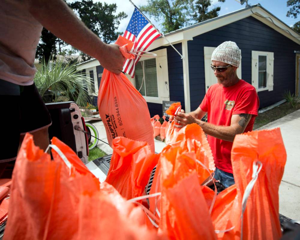 Tom Sikes, right, helps his friend Joey Spalding, left, fill sandbags at Spalding's home in Tyb ...