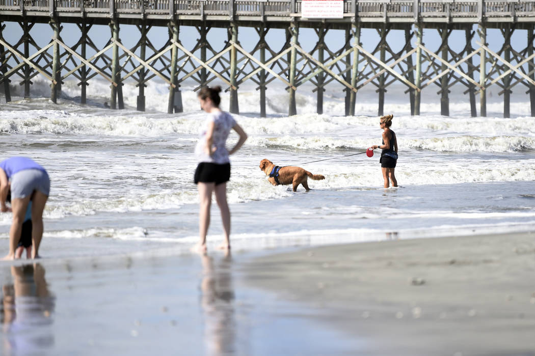 People walk near the pier at Folly Beach, S.C.,, Tuesday, Sept. 3, 2019, ahead of the arrival o ...