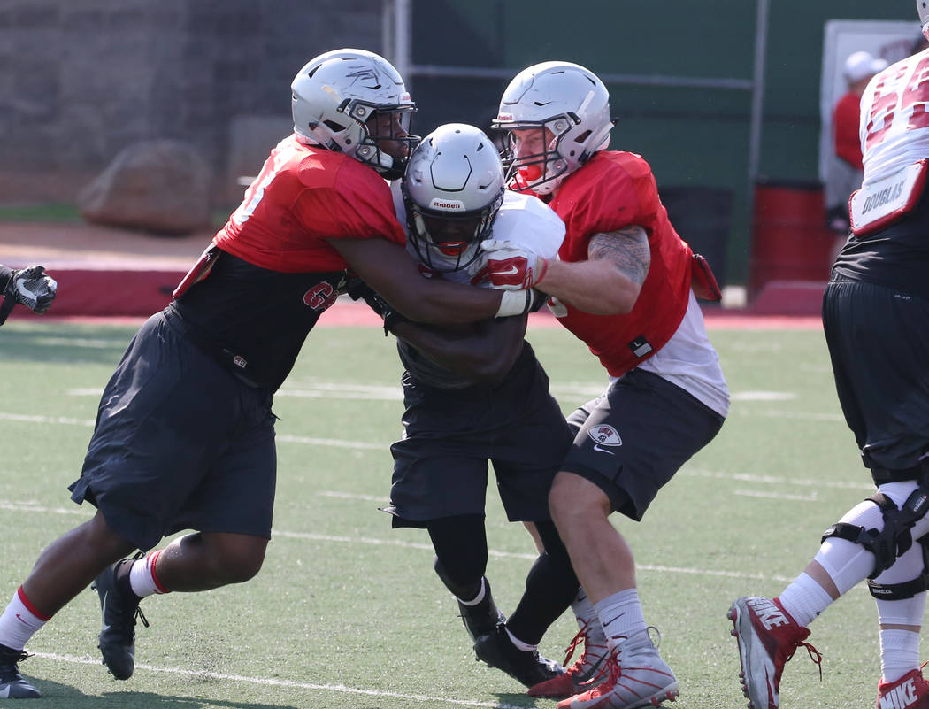 UNLV running back Charles Williams, center, tackled by linebackers Farrell Hester II, left, an ...