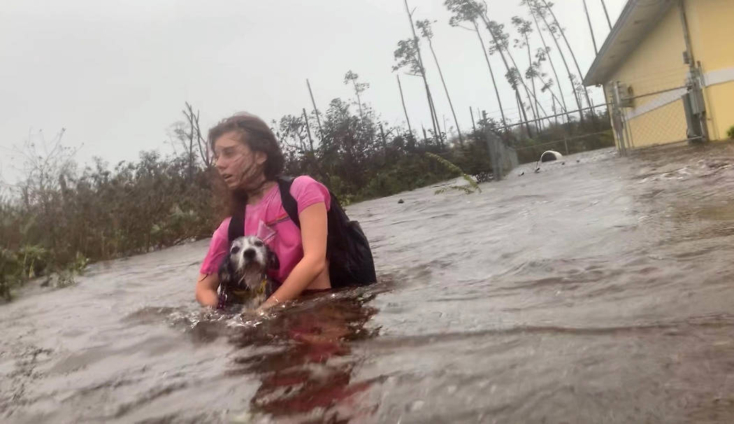 Julia Aylen wades through waist deep water carrying her pet dog as she is rescued from her floo ...