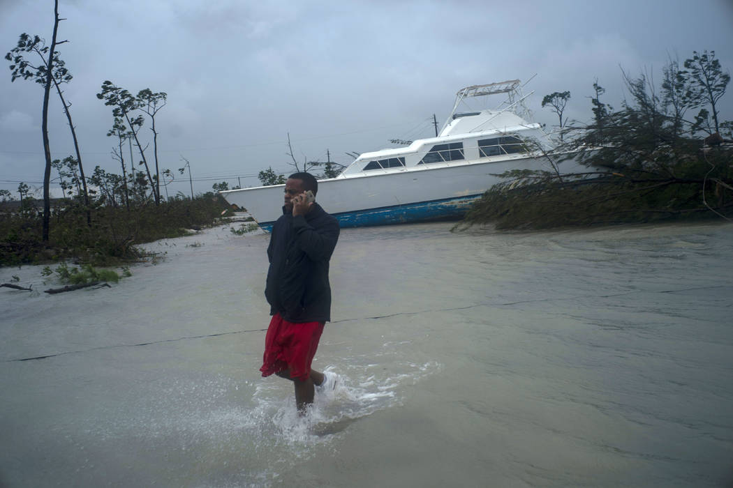 A man talks on his mobile phone next to a catamaran that was thrown onshore by the Hurricane Do ...