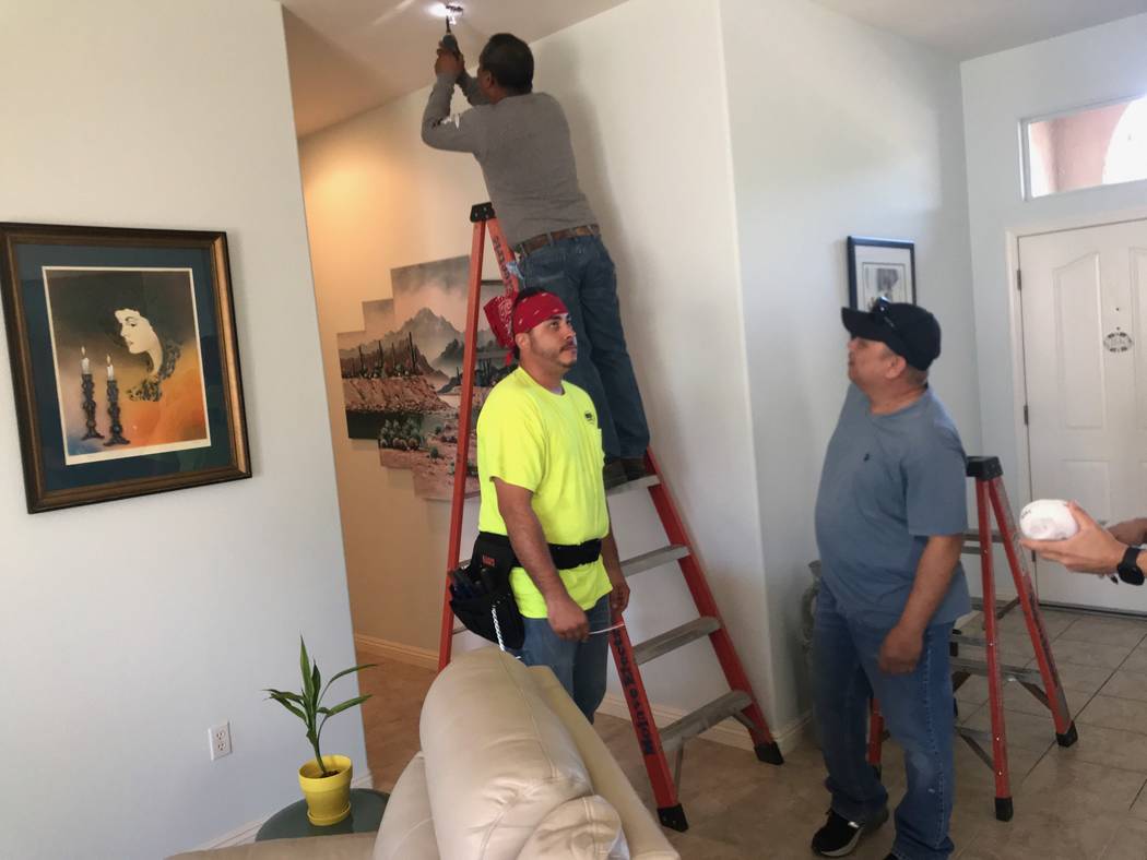 Three of Mojave Electric's licensed electricians work on installing a smoke alarm. On the ladde ...