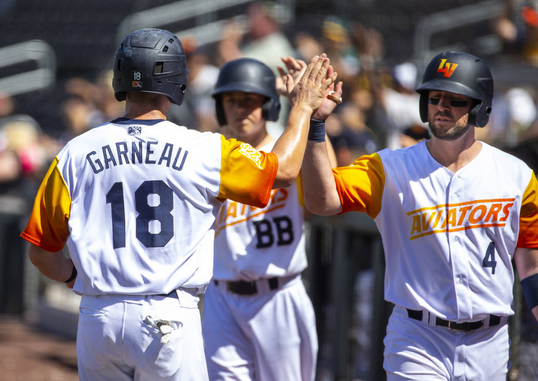 Las Vegas Aviators catcher Dustin Garneau (18) is congratulated on scoring by third baseman Mik ...