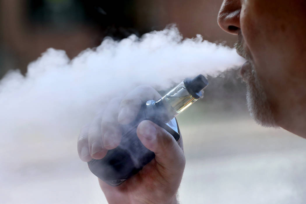 File - In this Aug. 28, 2019, file photo, a man exhales while smoking an e-cigarette in Portlan ...