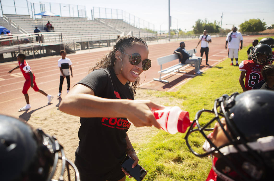 Alvina Conway, left, supplies water for TMT Red Lions player Anthony Rebel, right, and other p ...