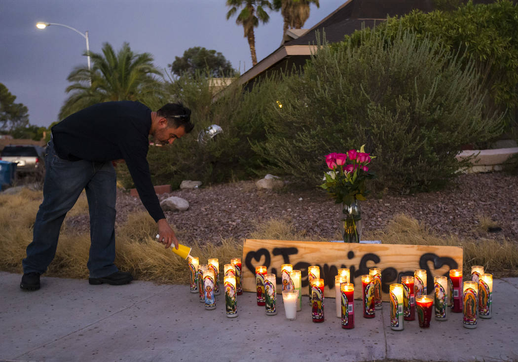 Carlos Gonzalez, a longtime family friend of Jennifer Ratay, lights a candle before the start o ...