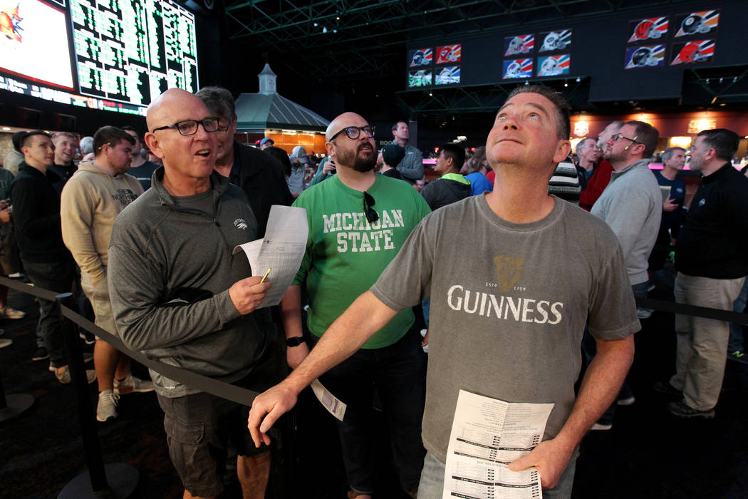 Steve Buckley of Boston, right, lines up to bet on basketball games during the NCAA Tournament ...