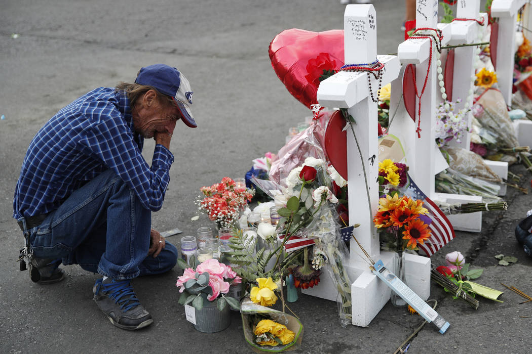 FILE - In this Aug. 6, 2019 file photo, Antonio Basco cries beside a cross at a makeshift memor ...