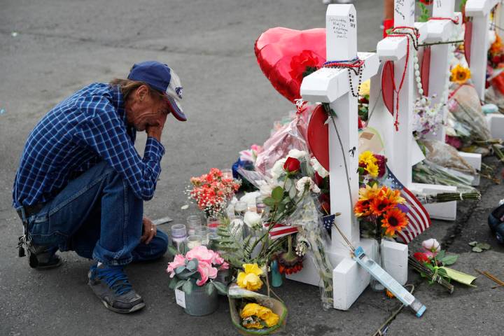 FILE - In this Aug. 6, 2019 file photo, Antonio Basco cries beside a cross at a makeshift memor ...