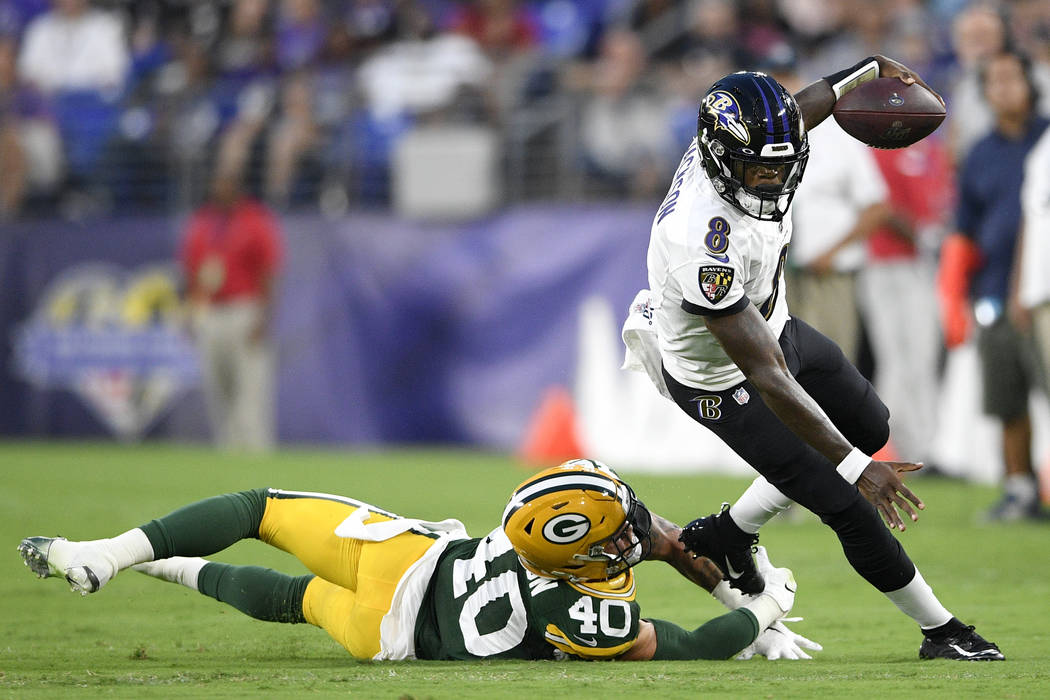 Baltimore Ravens quarterback Lamar Jackson, right, avoids a hit fromGreen Bay Packers linebacke ...