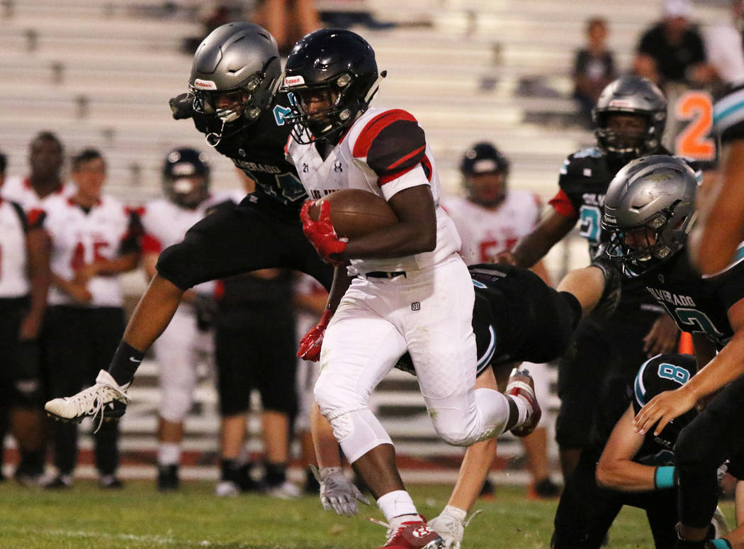 Las Vegas High's Jay Curtis (5) scrambles away from Silverado High's quarterback Ryan Kelly (8) ...