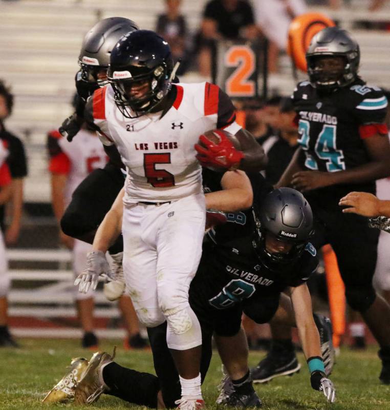 Las Vegas High's Jay Curtis (5) scrambles away from Silverado High's quarterback Ryan Kelly (8) ...