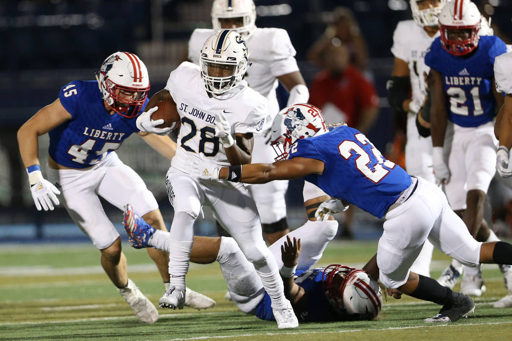 St. John Bosco's Michael Hayes (28) runs the ball against Liberty's Jayden Rookhuyzen (45), Tre ...