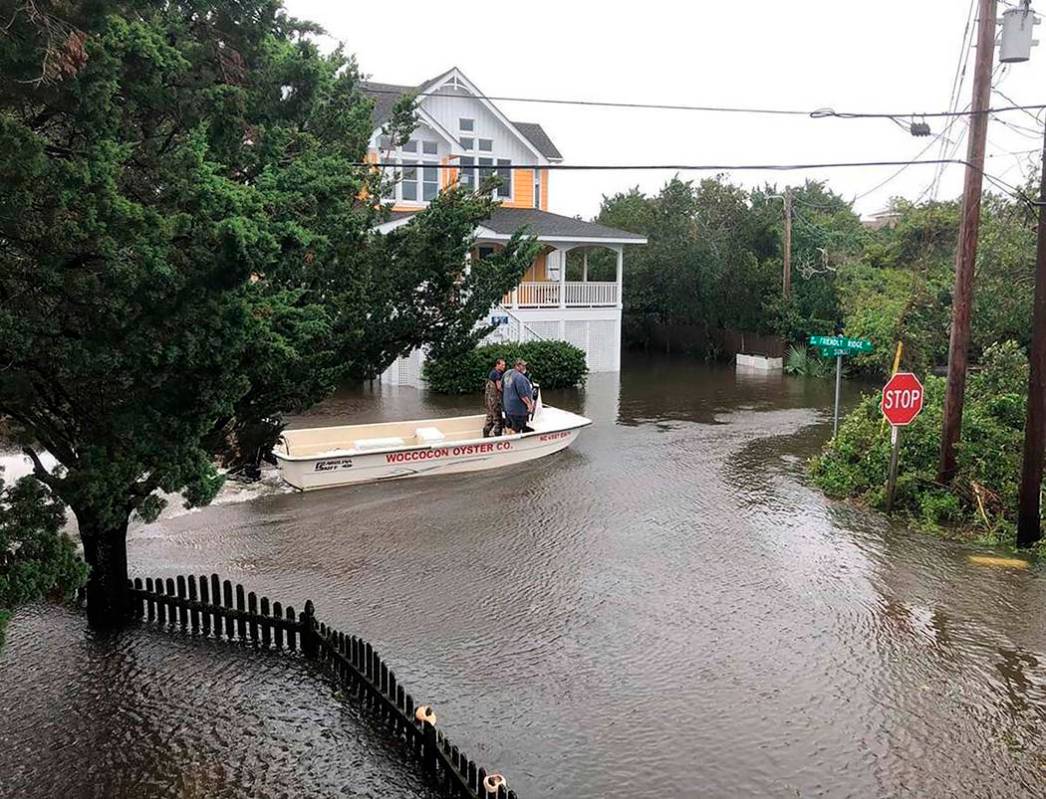 Ocracoke Volunteer Fire Department chief Albert O’Neal, in blue shirt, boats down Sunset ...