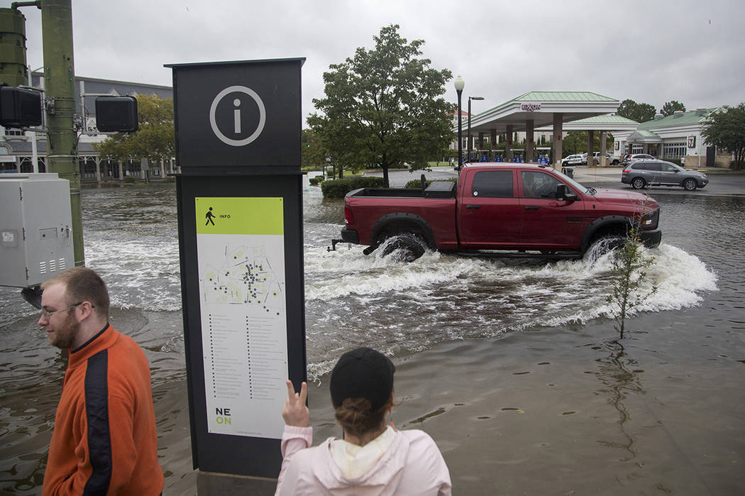 Emily Enyeart throws up a peace sign to a truck as it successfully passes through the flooding ...