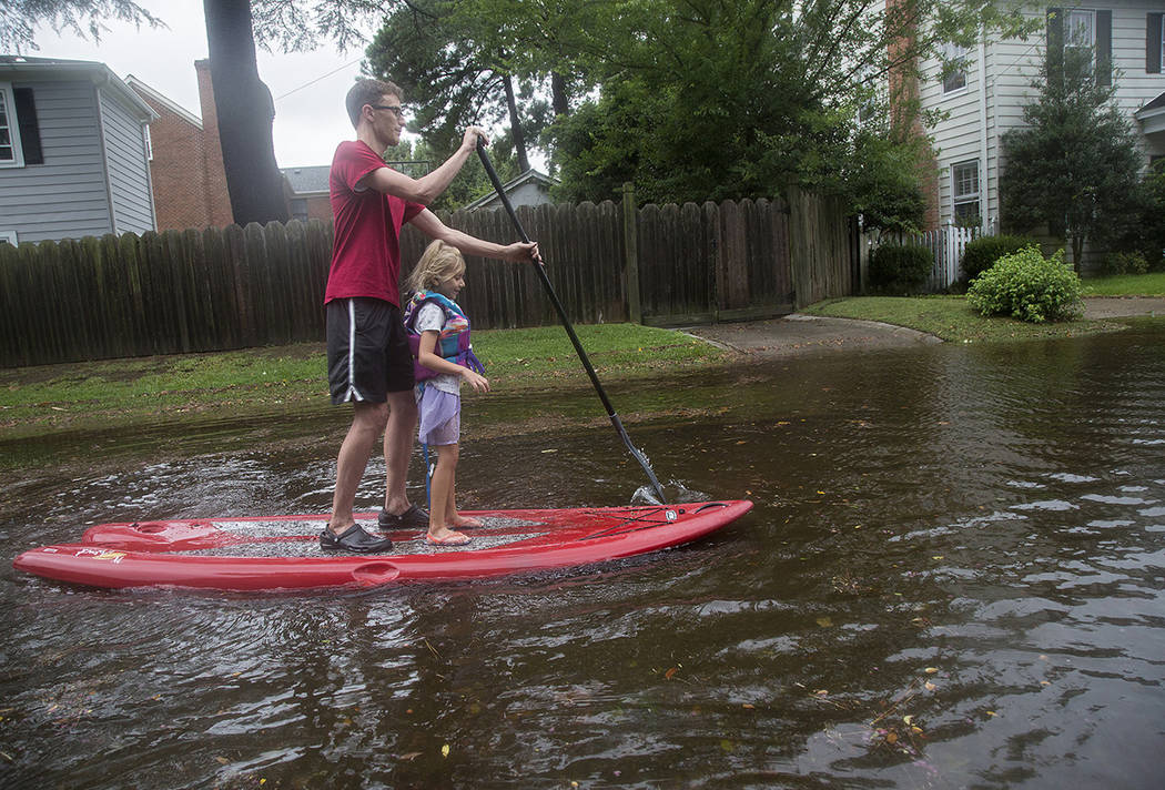 Eric Young stand-up paddleboards through flooded streets in Larchmont with his daughter, Emily ...